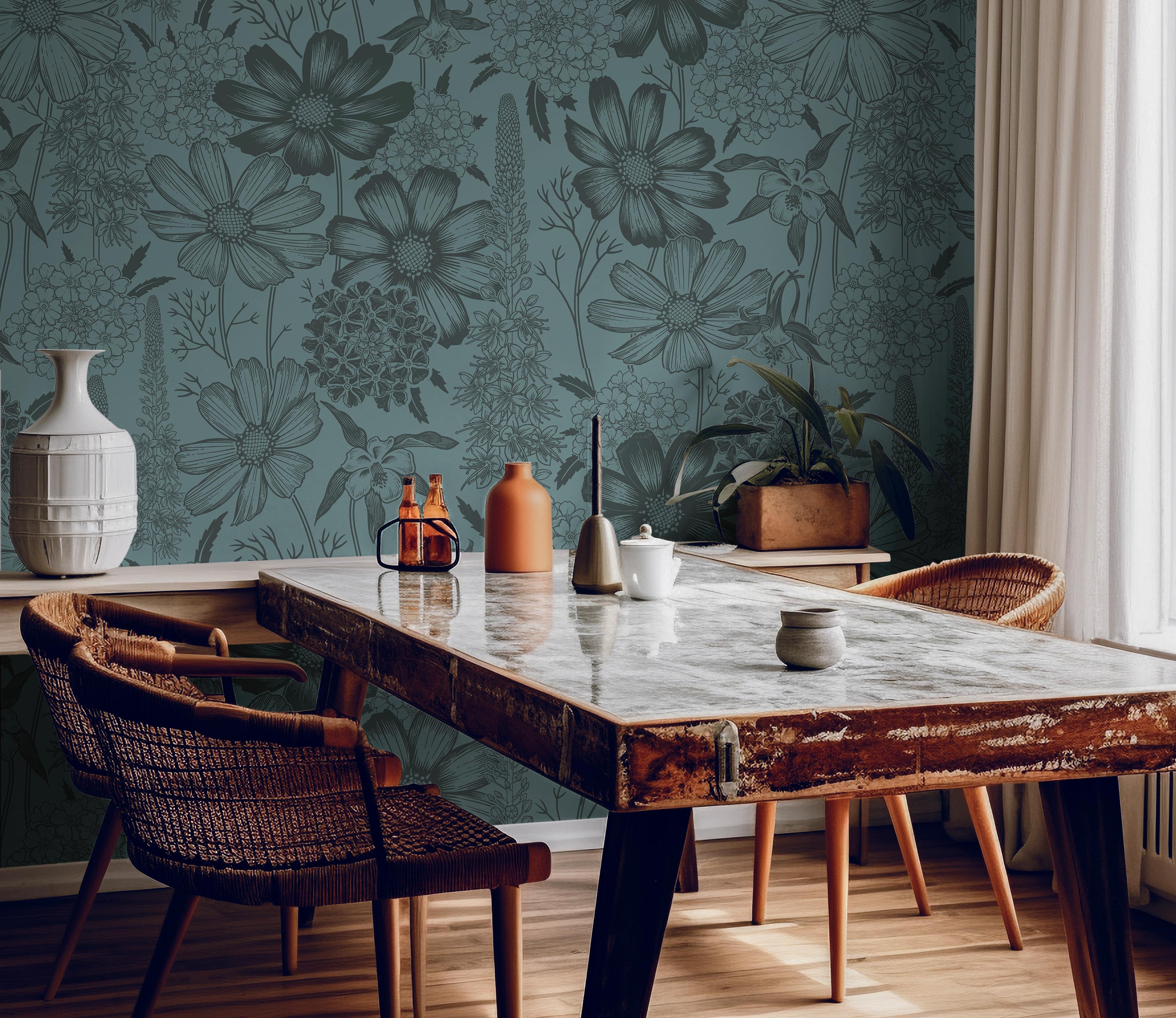Wallpaper 1482: Deep green wallpaper with hand-drawn botanical illustrations in a darker tone, featuring wildflowers and foliage, styled behind a rustic wooden dining table with woven chairs and natural decor.