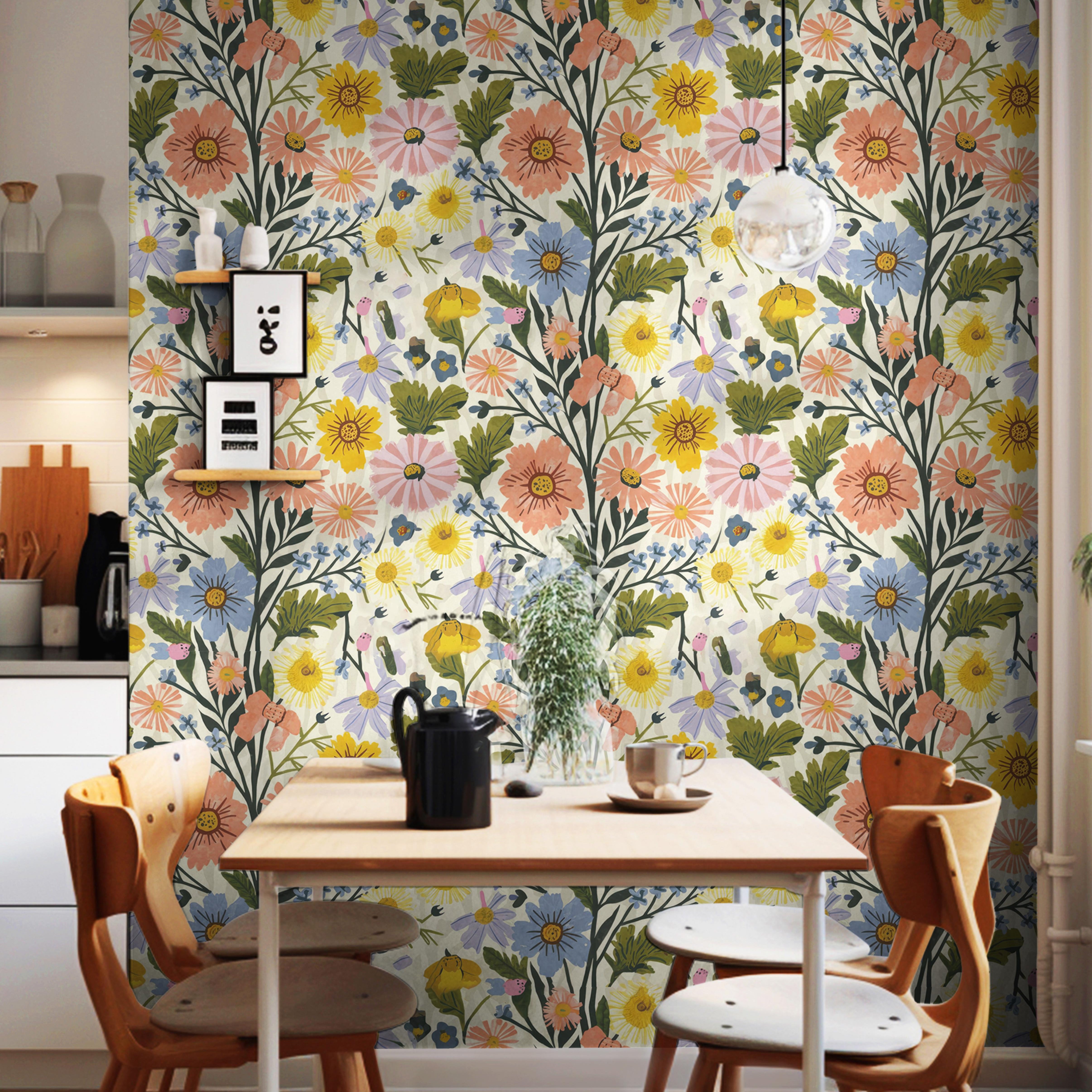 Floral Spring Vibes wildflower wallpaper in coral, yellow, blue and lavender on a dining nook wall with a wooden table and orange chairs