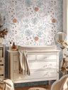 Wallpaper 1655: Soft floral wallpaper with hand-drawn blue, rust, and gray flowers in a nursery behind a white changing table and dresser, styled with warm neutral tones and natural light.
