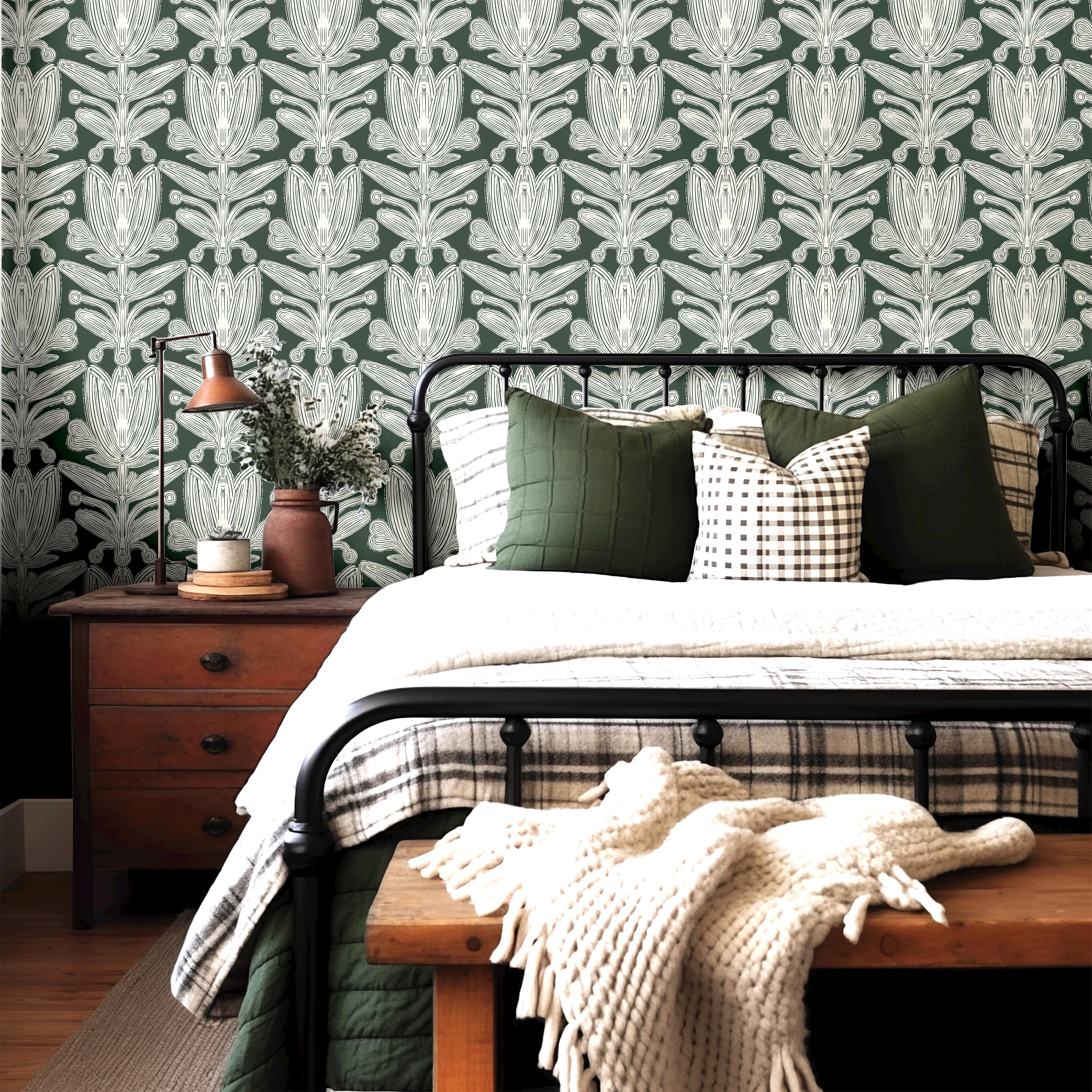 Wallpaper 1956: Vintage-inspired bedroom featuring a forest green botanical wallpaper with symmetrical cream floral pattern, behind a black iron bed and earthy wood nightstand.