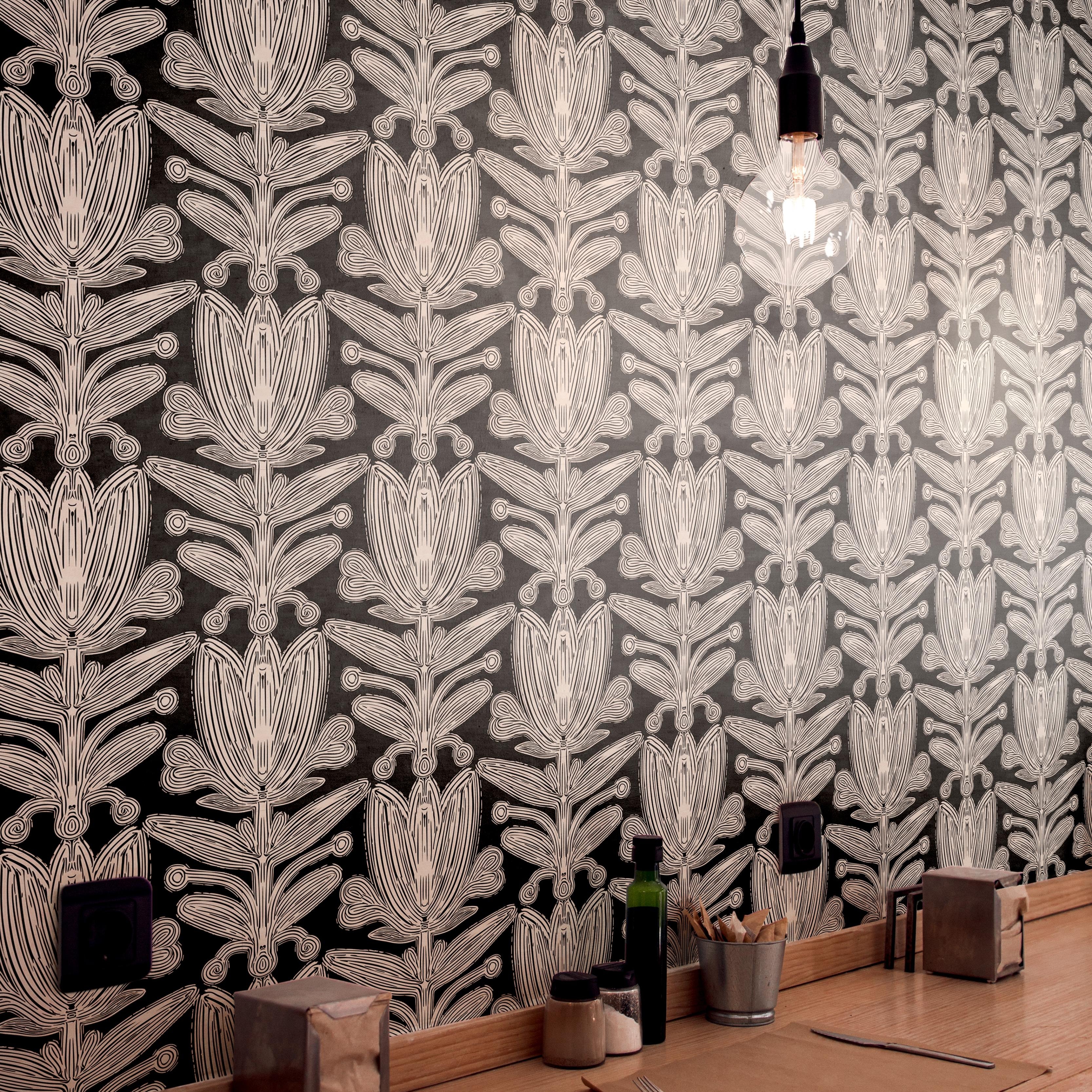 Wallpaper 1960: Black wallpaper with bold, abstract floral line art in vertical columns, creating a dramatic symmetrical look behind a light wood cafe counter.