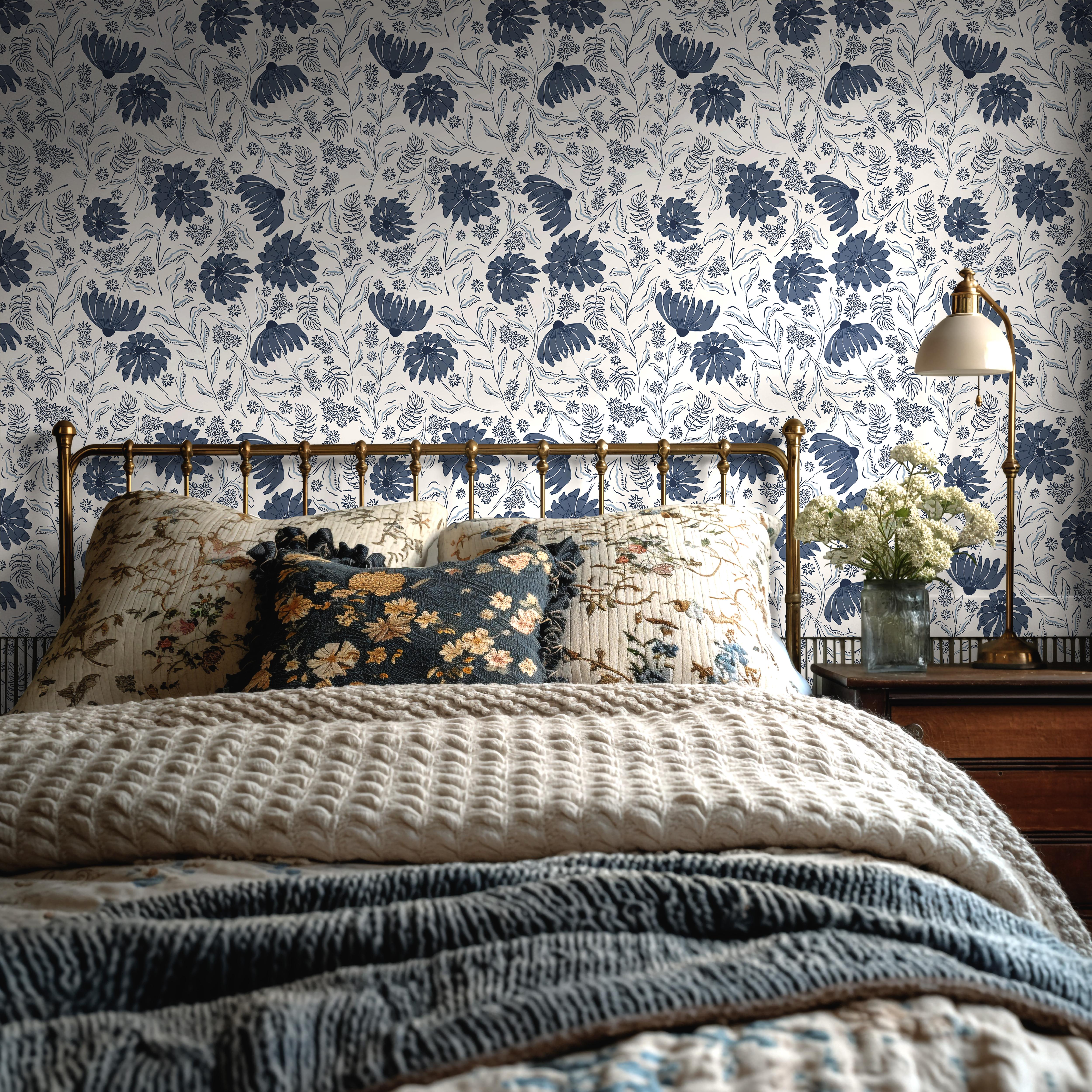 Wallpaper 1970: Vintage-style bedroom with brass bedframe and navy floral wallpaper featuring blue botanical blooms and cream background, styled with layered floral bedding and cozy textures.