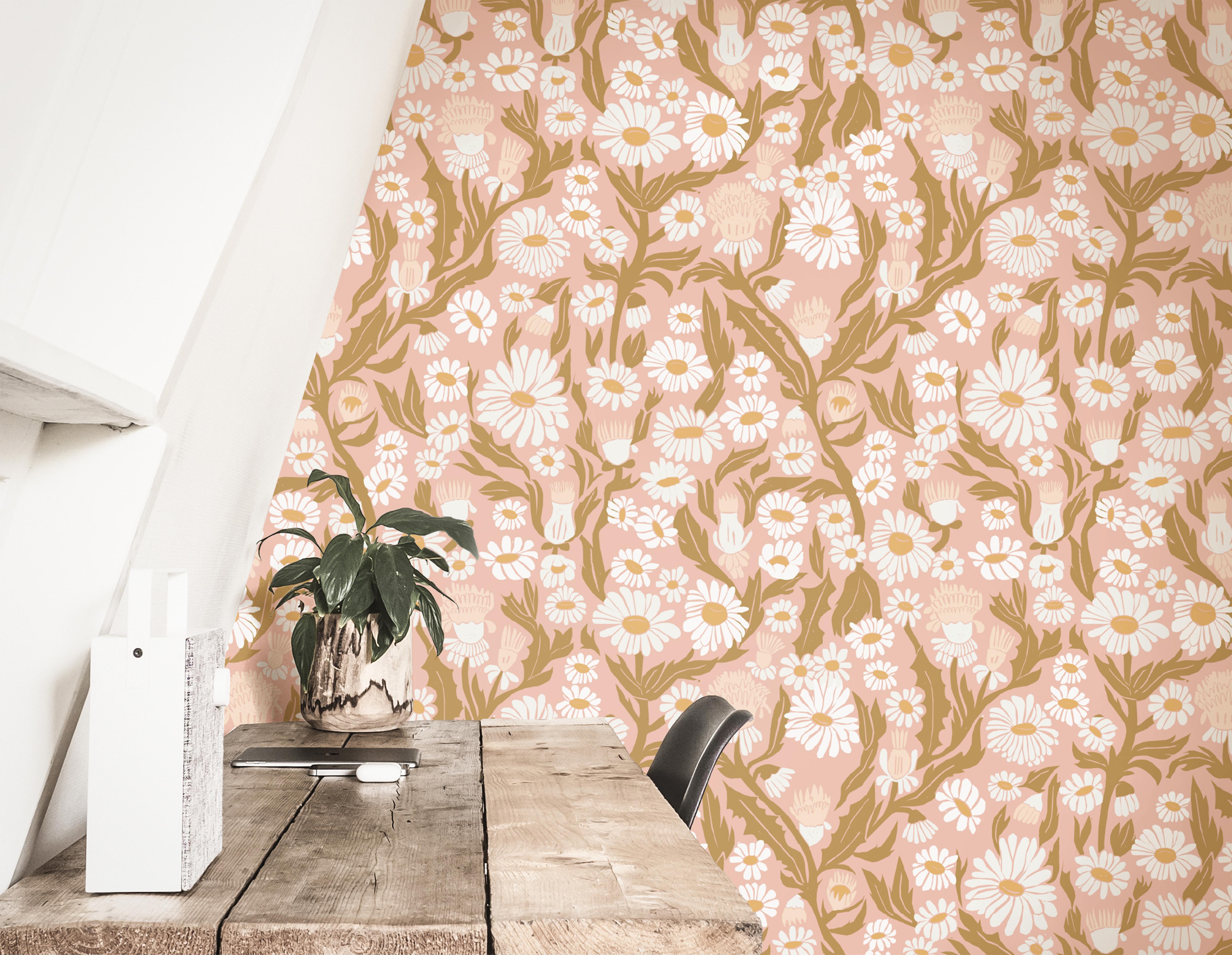 Wallpaper 1981: Blush pink daisy wallpaper with golden leaves in a cozy boho workspace.