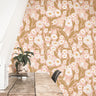 Wallpaper 1981: Blush pink daisy wallpaper with golden leaves in a cozy boho workspace.
