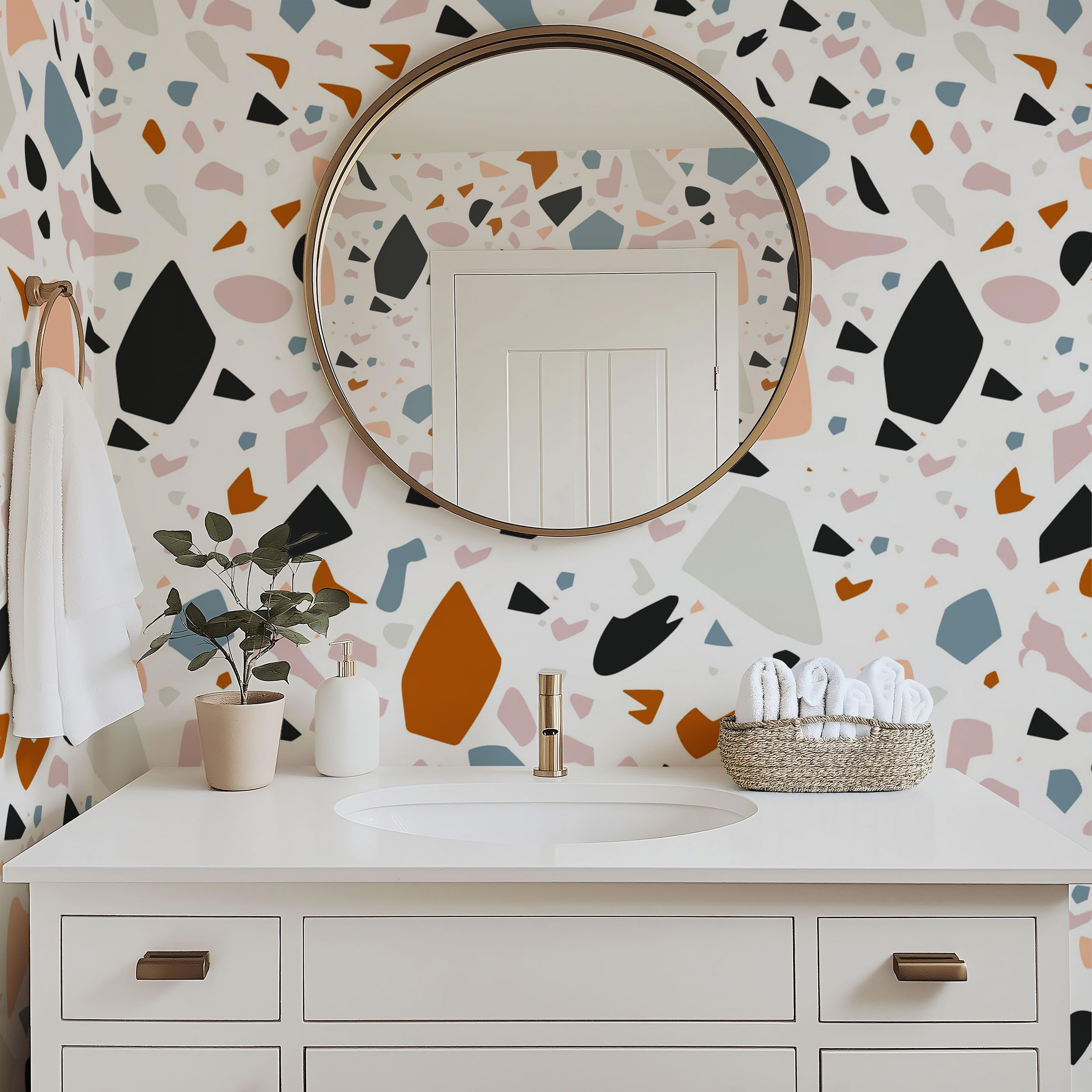 Wallpaper 1988: Modern bathroom with a white vanity and mirror, featuring terrazzo-style wallpaper in a bold mix of burnt orange, black, blush pink, slate blue, and beige abstract shapes on a white background.