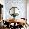 Wallpaper 2010: Wallpaper with a clean white background and intricate blue floral-geometric designs, styled in a modern dining area with a round mirror, natural wood furniture, and soft Scandinavian decor.