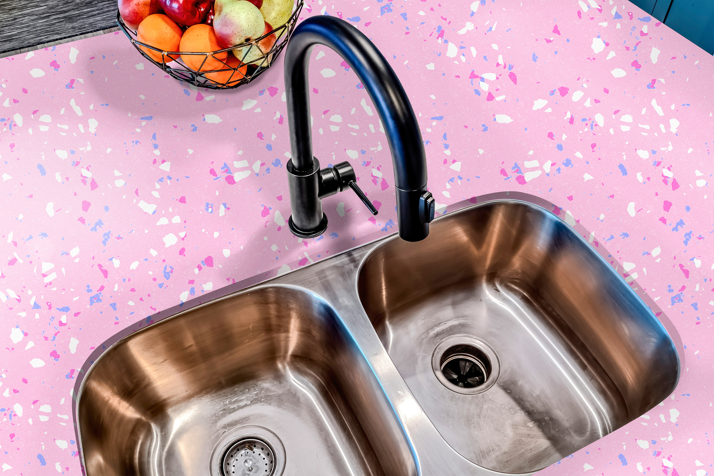 Countertop film 55: A close-up of a pink terrazzo countertop film applied to a kitchen counter with a stainless steel sink. The speckled adhesive film features white, pink, and blue flecks, creating a modern terrazzo pattern for stylish kitchen decor.