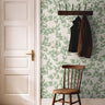 Bright green airy leaves styled with dark wood accents in a warm hallway