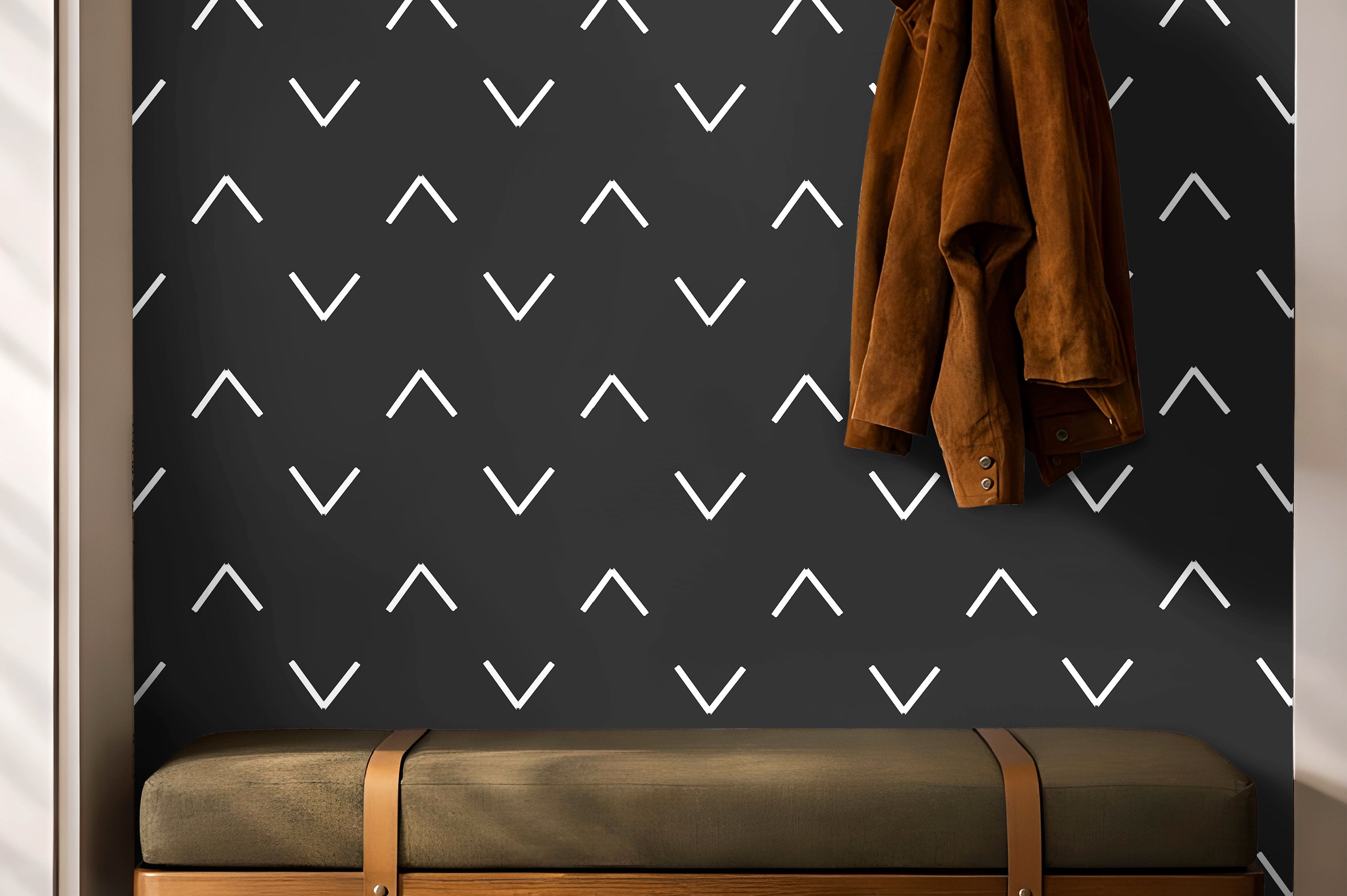 Black background with white chevrons in geometrical wave pattern in entryway with hooks and green bench