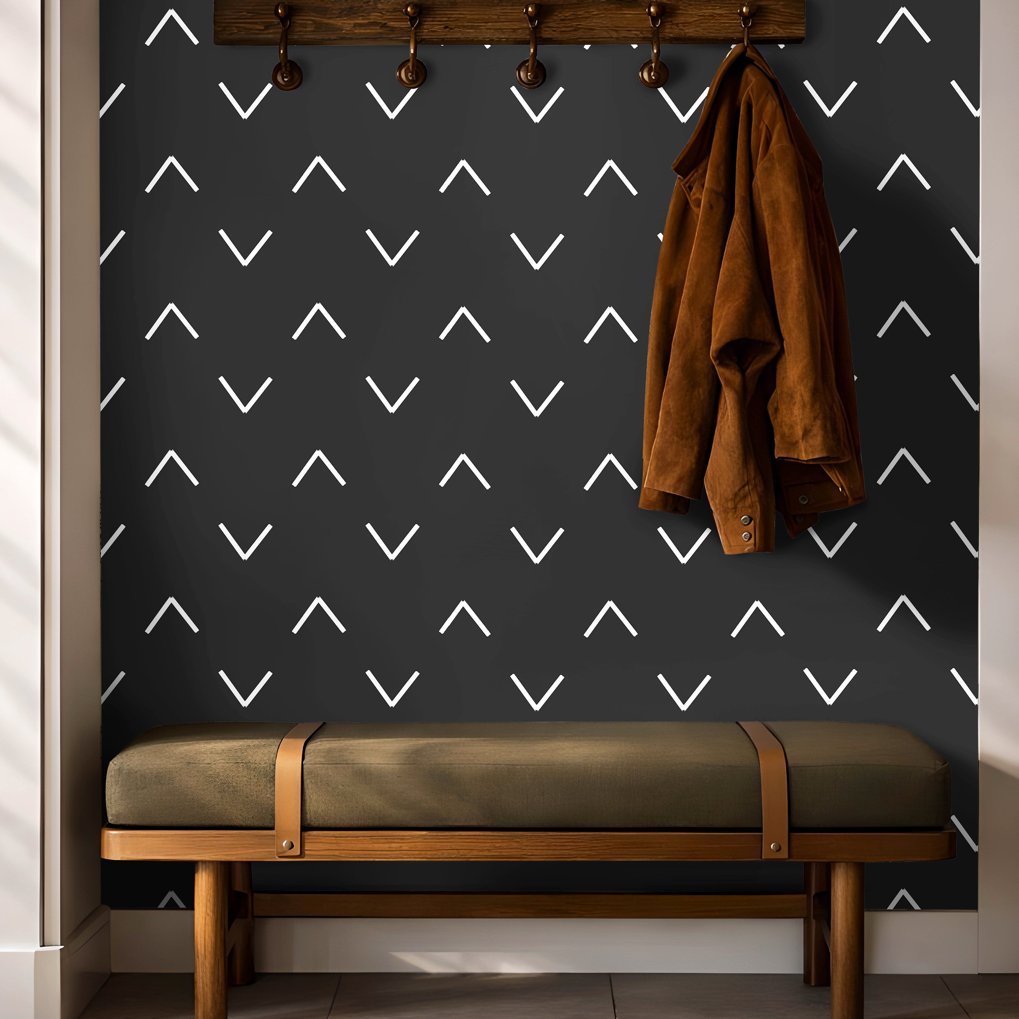 Black background with white chevrons in geometrical wave pattern in entryway with hooks and green bench