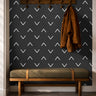 Black background with white chevrons in geometrical wave pattern in entryway with hooks and green bench