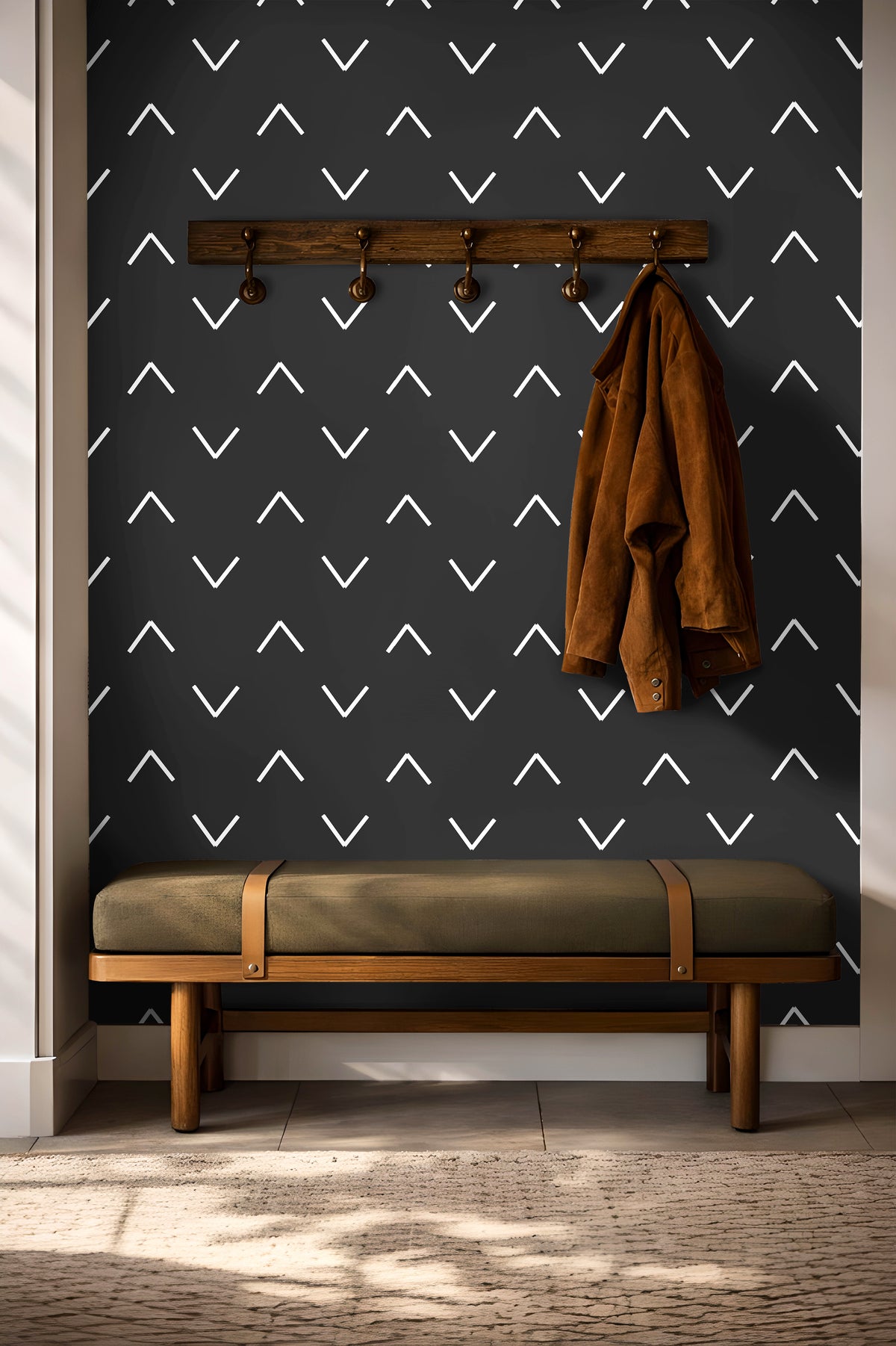 Black background with white chevrons in geometrical wave pattern in entryway with hooks and green bench