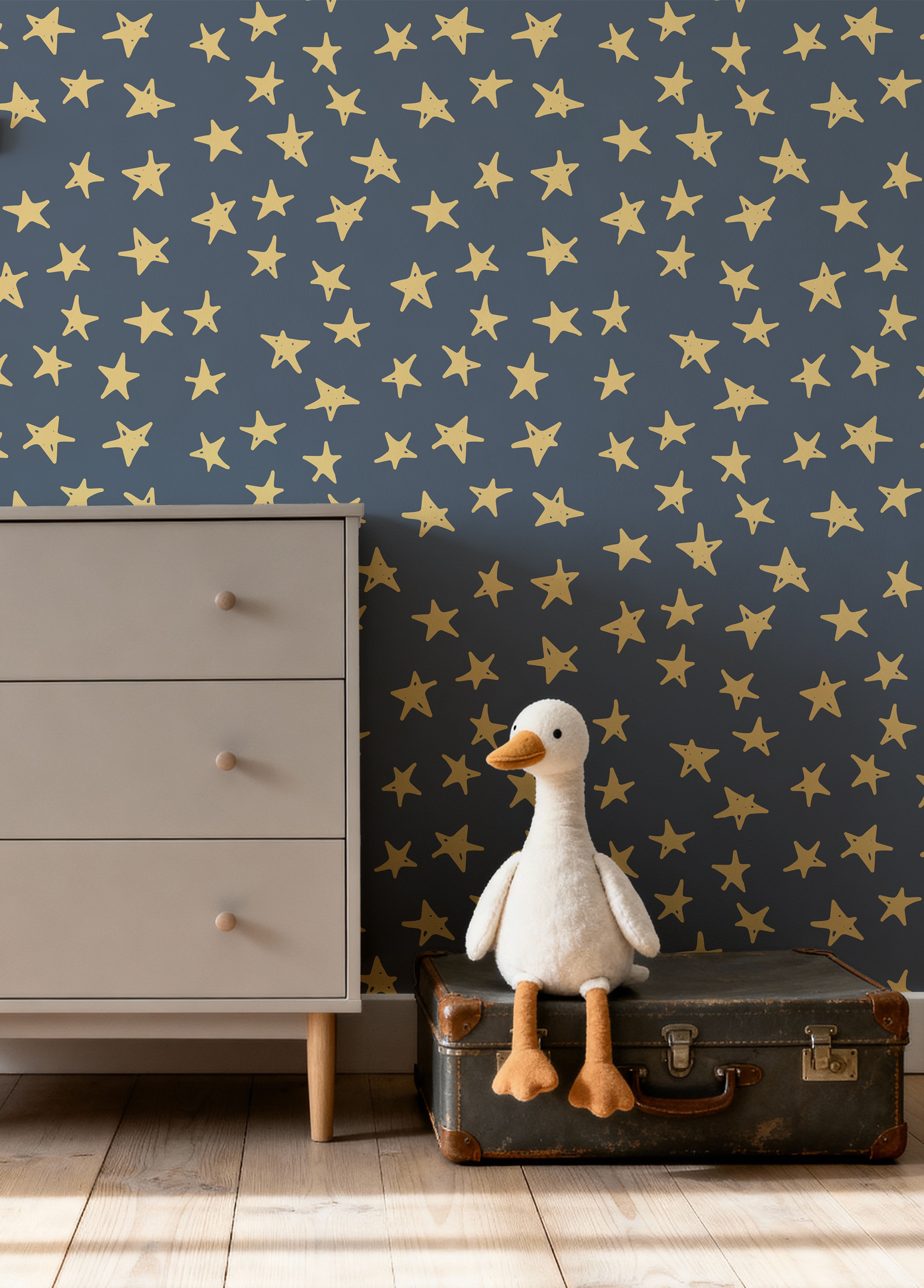 Deep blue background with yellow crayon drawn stars in kids room with dresser and a stuffed goose on top of a suitcase