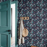 Dark navy background with teal leaves and white and purple flowers in entryway with teal door