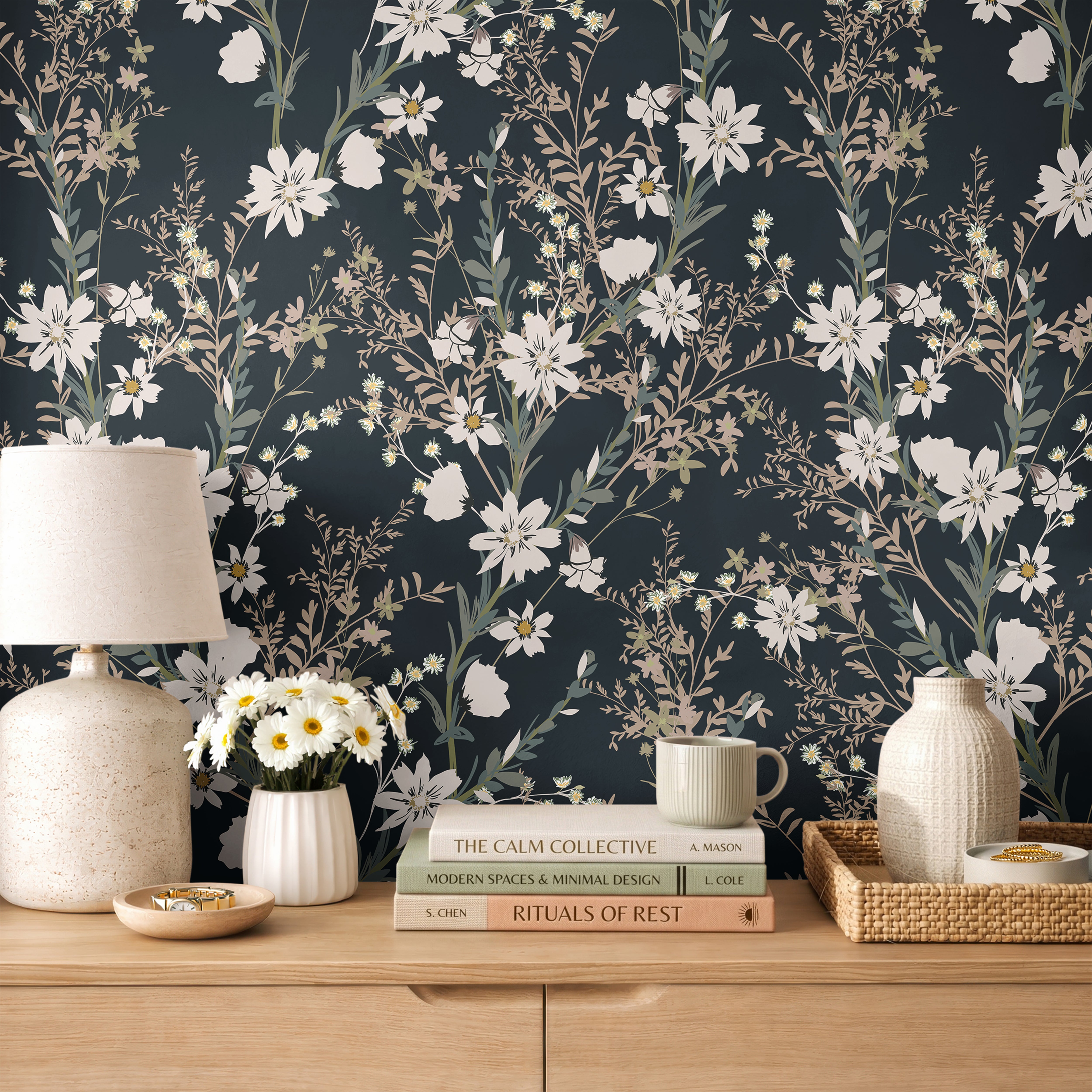 Dark teal floral wallpaper with soft ivory wildflowers and muted green foliage styled above a natural wood dresser with neutral ceramic decor.
