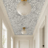 oversized botanical blooms drawn in graceful charcoal linework over a smooth ivory background in modern white hallway 