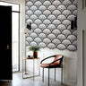 charcoal and blush art deco wallpaper above white paneling with black door brass table and rust chair