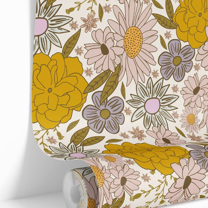 Roll of Butterbloom Field Wallpaper showing golden, blush, and cream floral pattern inspired by daisies and marigolds.