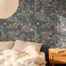 Moody botanical wallpaper with slate blue florals and olive branches in a warm modern bedroom interior.