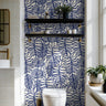 Blue botanical wallpaper with oversized tropical foliage styled in a bright coastal bathroom.
