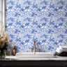 Tropical coastal wallpaper with hand drawn palm trees and ocean waves styled in bathroom with brass accented interior.