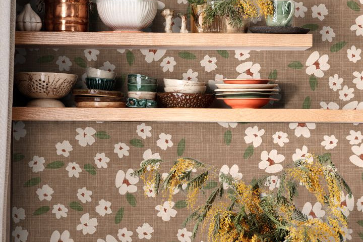 Floral wallpaper with ivory blooms and sage green leaves on a warm taupe background in a styled kitchen interior