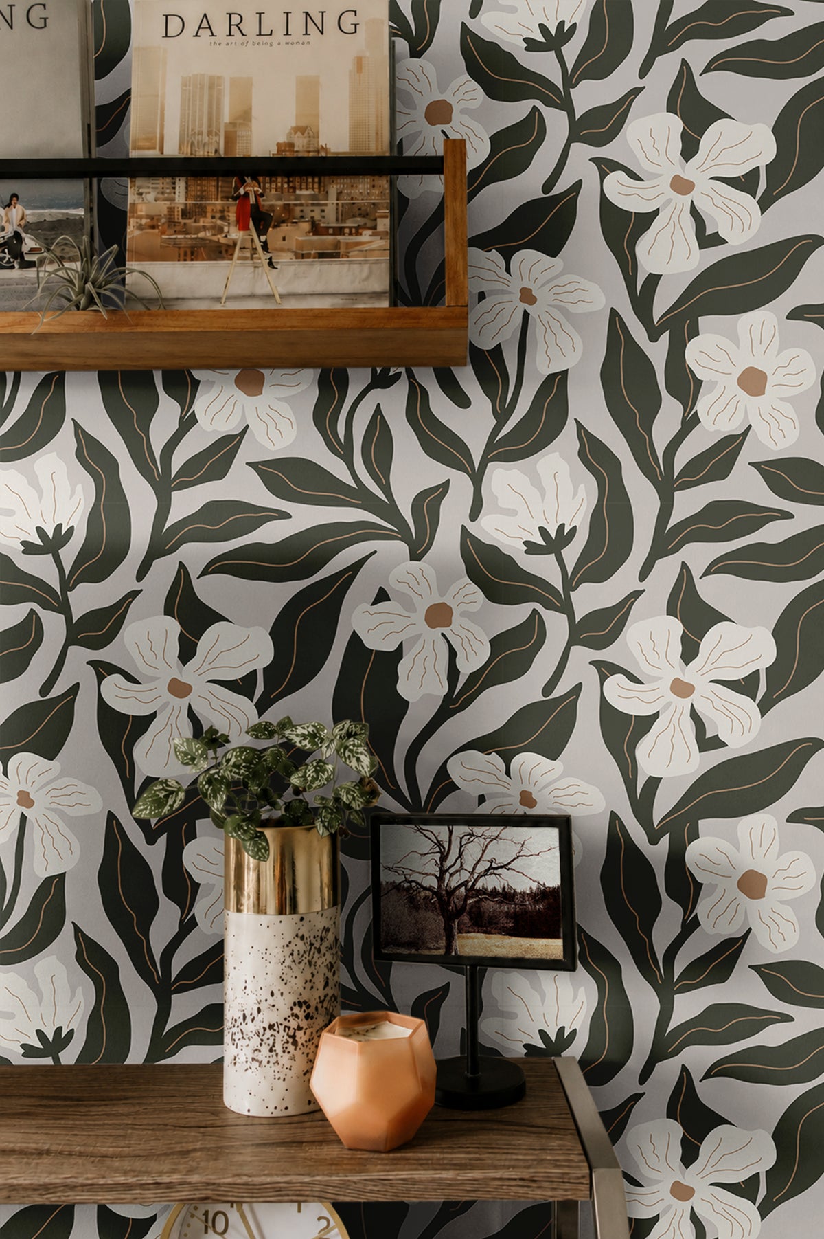  ivory flowers with tan centers and dark olive leaves on a pale wallpaper background behind warm wooden shelves
