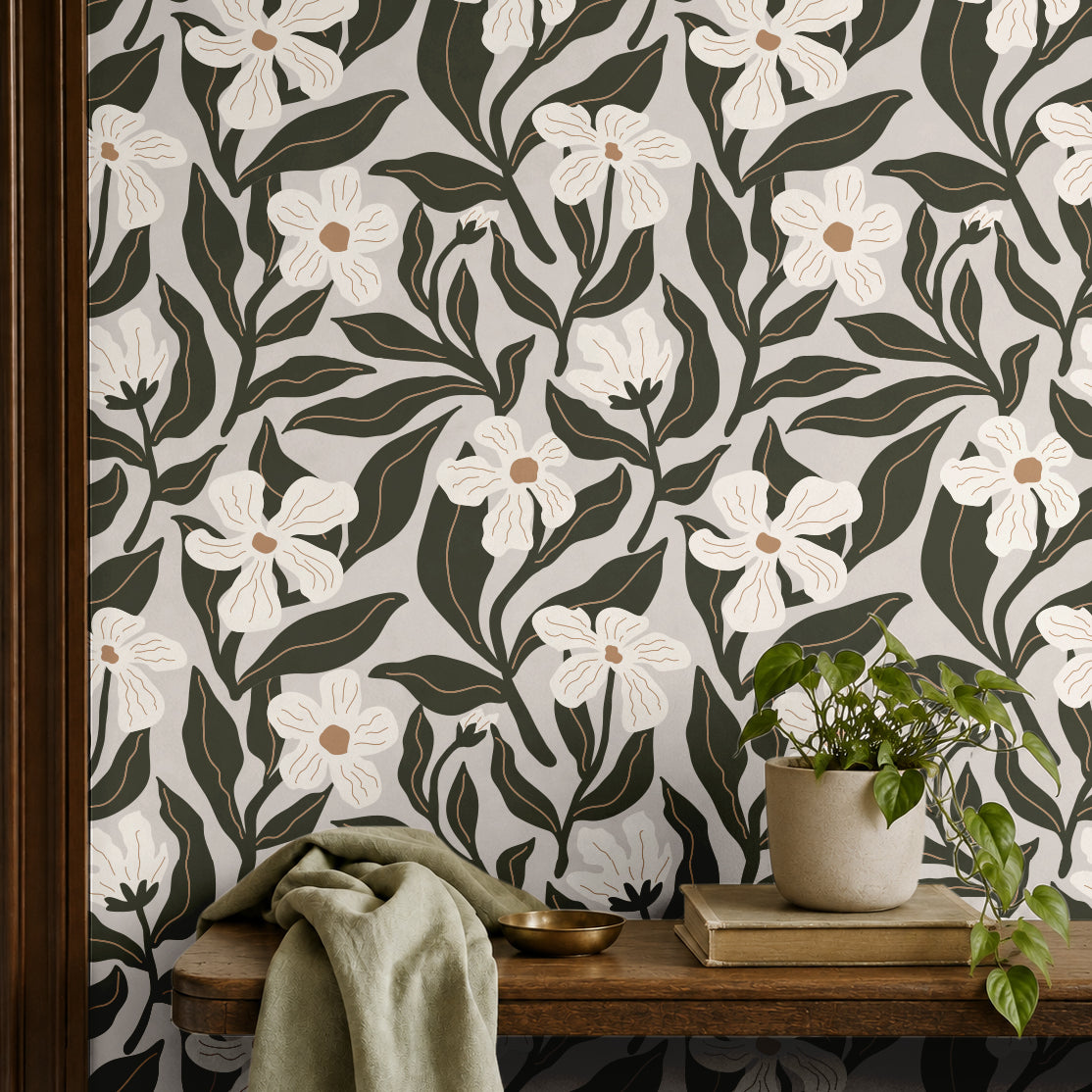 ivory floral wallpaper with dark olive leaves behind a wood shelf with potted plant