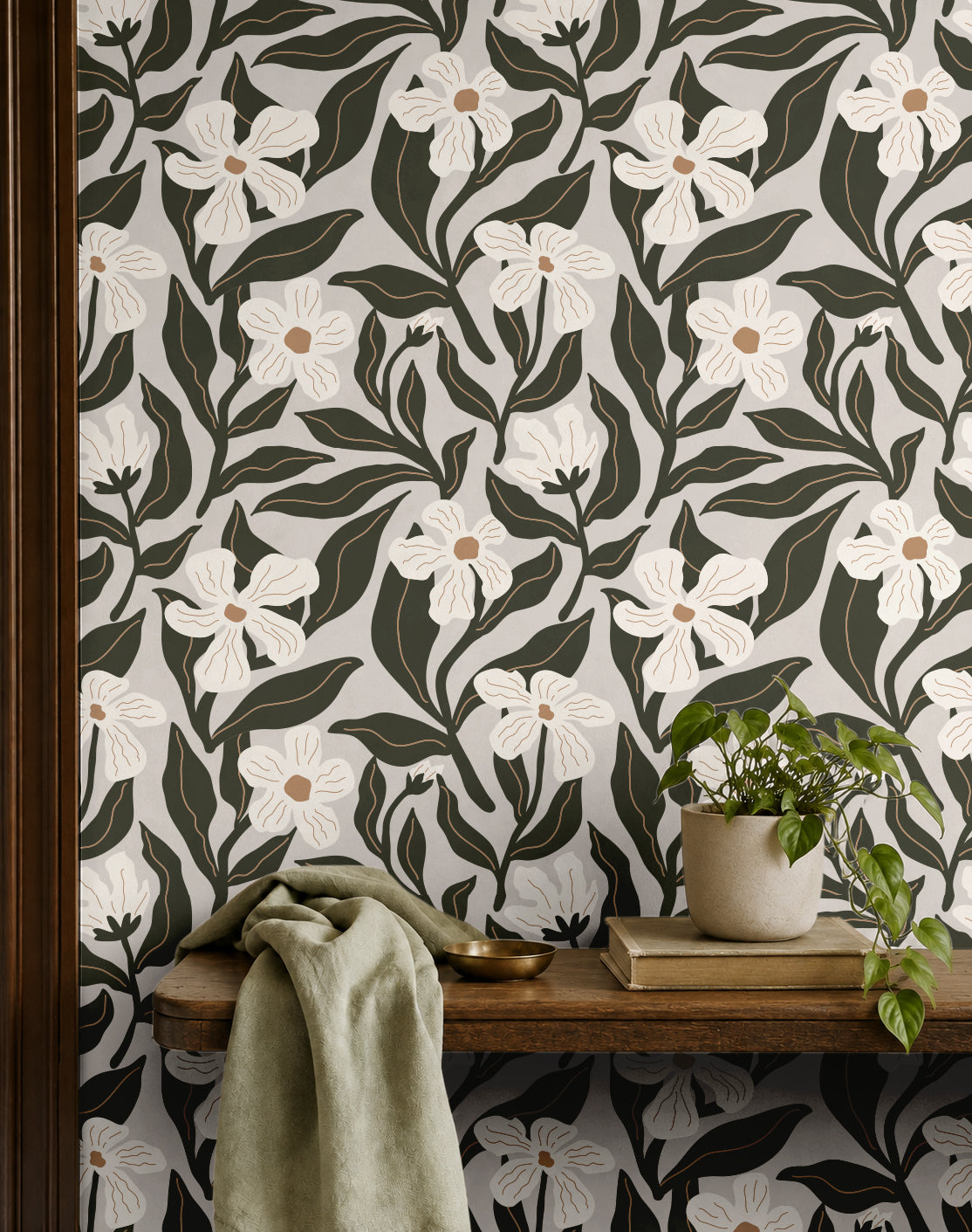 ivory floral wallpaper with dark olive leaves behind a wood shelf with potted plant