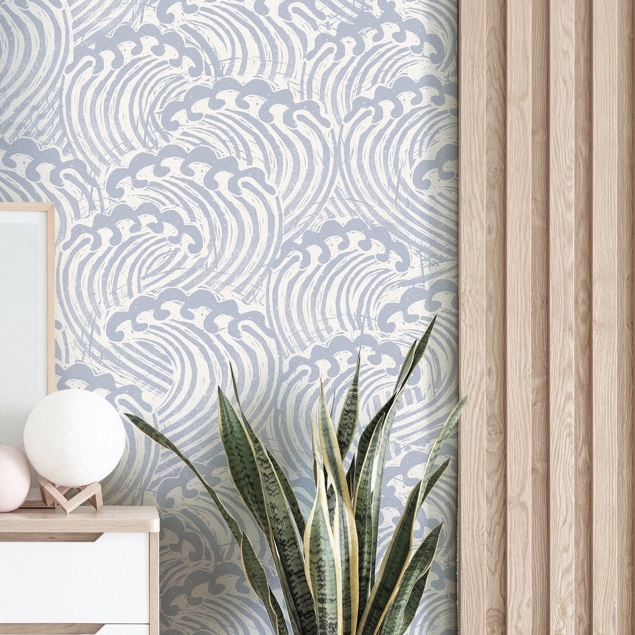 muted blue wave wallpaper beside pale wood slat wall with white cabinet globe lamp and snake plant