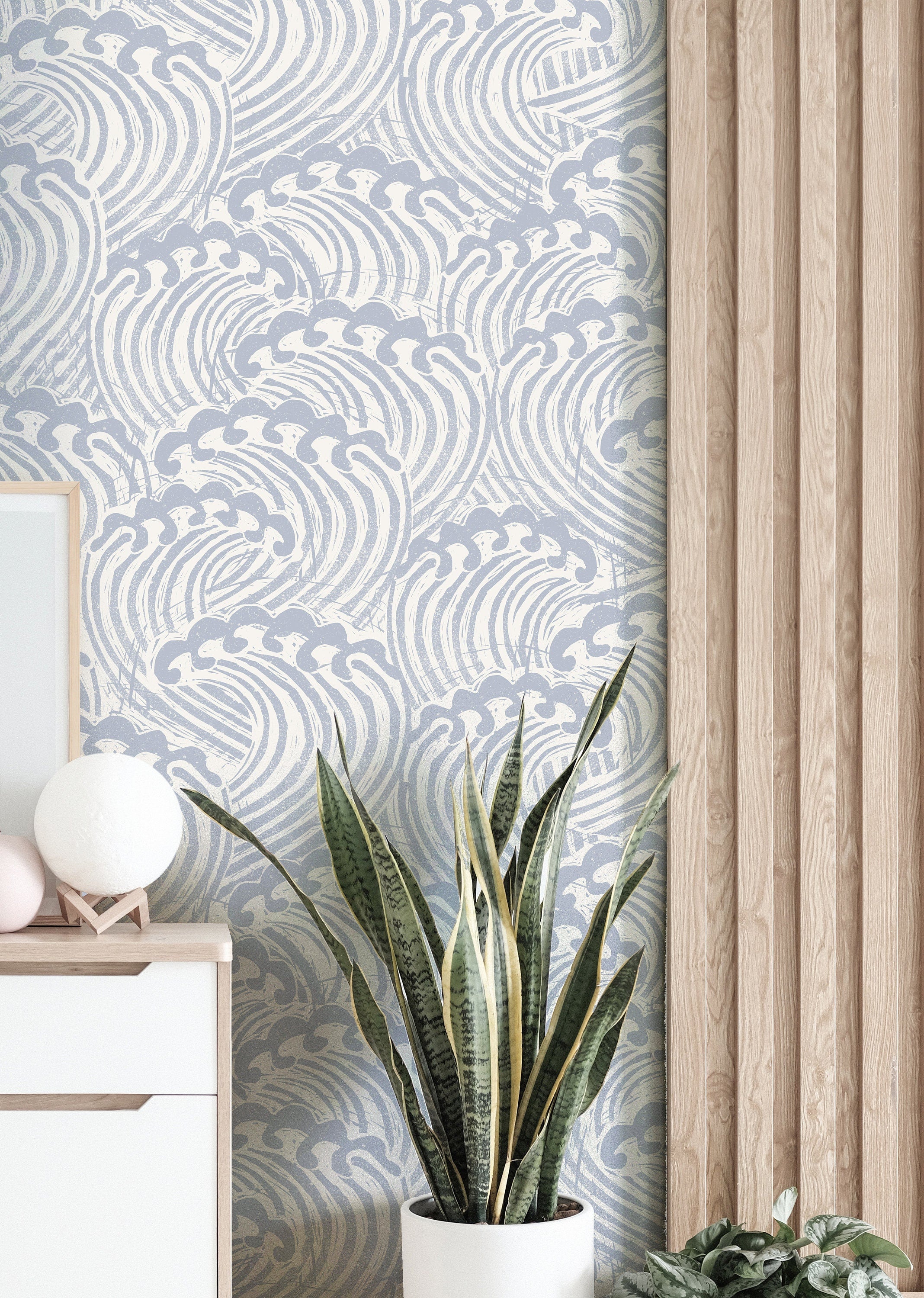 muted blue wave wallpaper beside pale wood slat wall with white cabinet globe lamp and snake plant