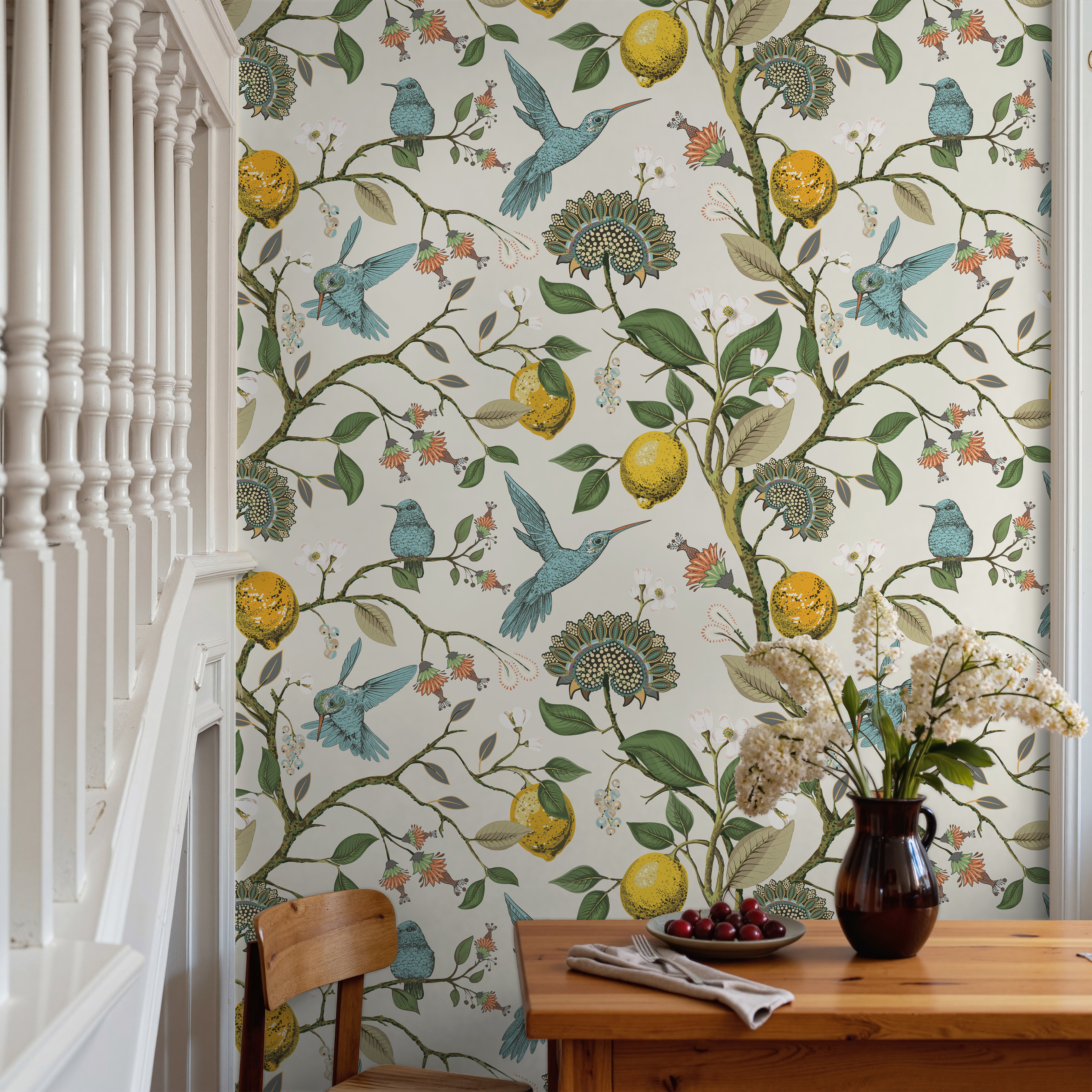 Hummingbird wallpaper featuring colorful birds, soft florals, and botanical branches styled in a bright collected dining room with warm natural textures.