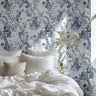 Indigo Meadow wallpaper behind bed with blue and white florals creating a calm, airy atmosphere