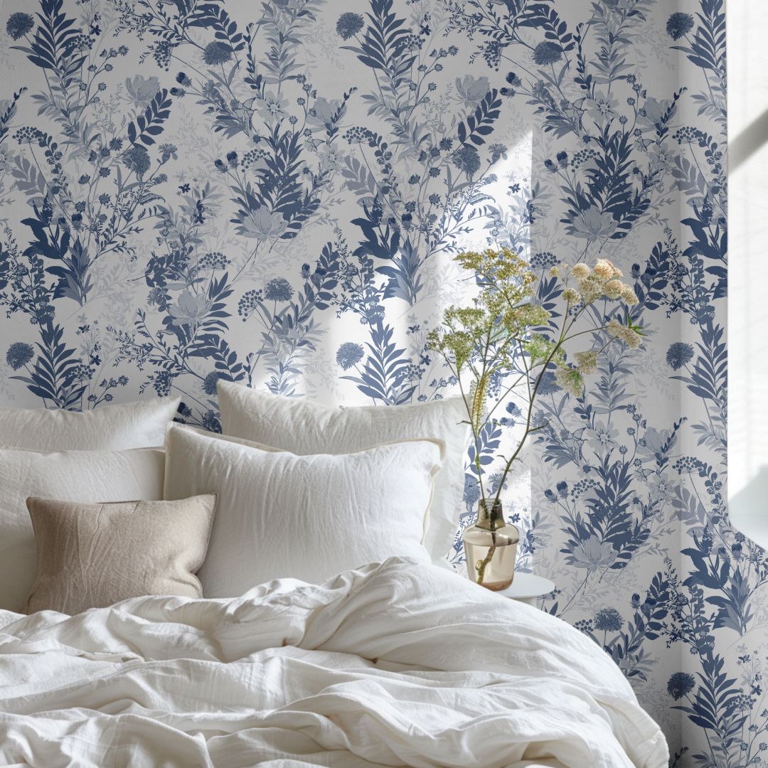Indigo Meadow wallpaper behind bed with blue and white florals creating a calm, airy atmosphere