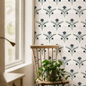 indigo and green art deco floral wallpaper beside window with wood chair and trailing plant