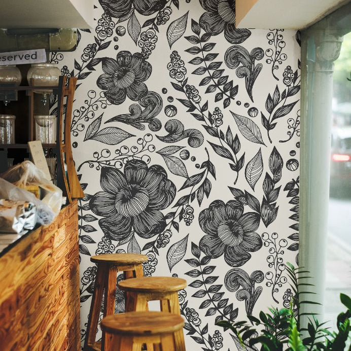 Inkwell Botanica black and ivory wallpaper in a cozy café setting with natural wood tones
