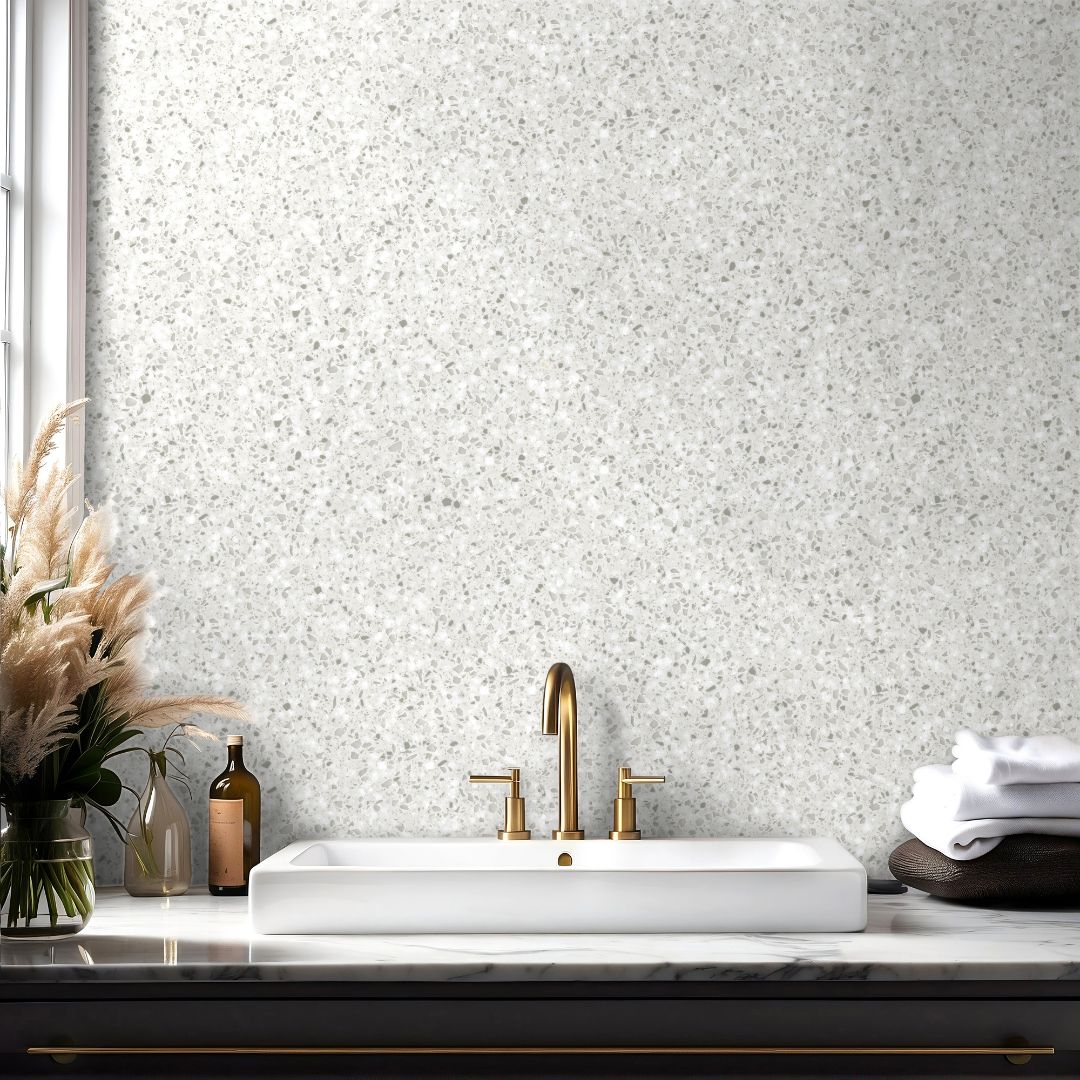 Light ivory terrazzo wallpaper with subtle stone texture in a modern bathroom with brass fixtures