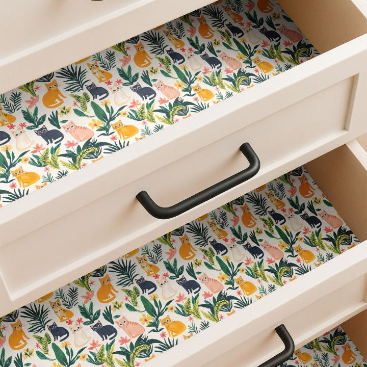 Drawer lined with playful cat and tropical leaf pattern in orange, blush, cream, and navy on a warm cream background