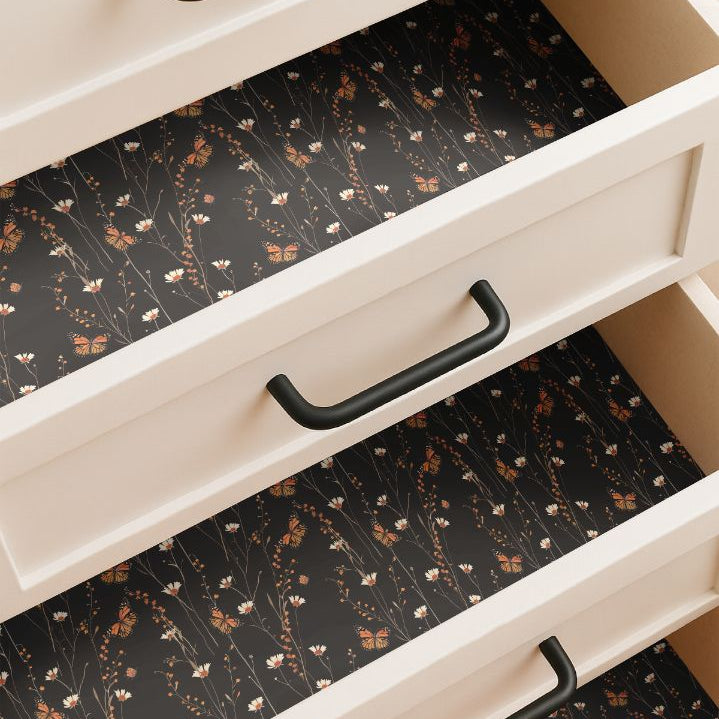 Drawer lined with monarch butterfly and wildflower contact paper on deep black background