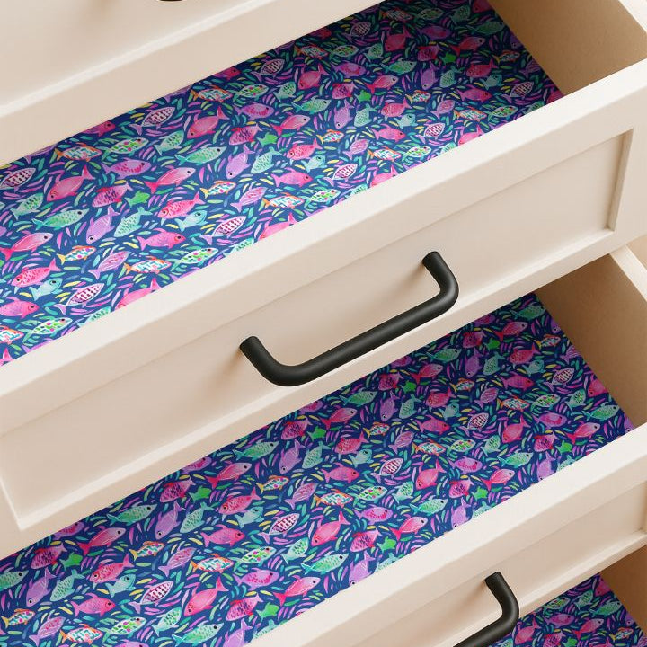 Drawer lined with colorful tropical fish contact paper featuring coral, aqua, and lime fish on blue background