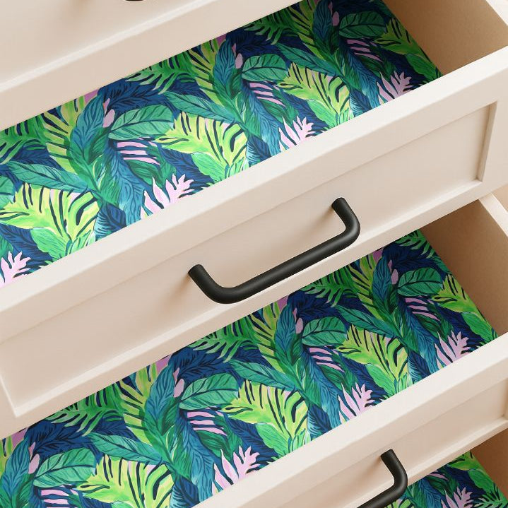 Drawer lined with tropical green and pink leaf pattern contact paper on a midnight blue background