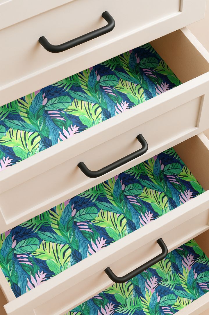 Drawer lined with tropical green and pink leaf pattern contact paper on a midnight blue background