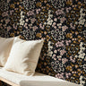 Mauve petal calico floral wallpaper with soft mauve and cream flowers on a dark background styled in an interior space.