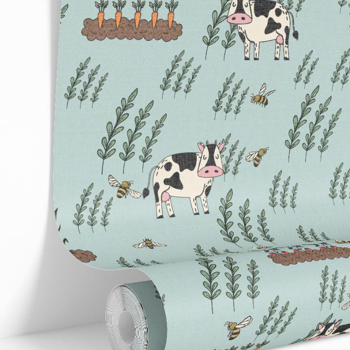 Close-up roll view of Moo Meadow Farm Wallpaper featuring cows, bees, and carrot garden illustrations on a soft blue-green background.