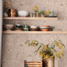 Open Bloom blush floral wallpaper with botanical line art in a warm kitchen with open wood shelving and green cabinets