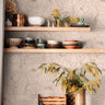 Line-drawn floral wallpaper in warm beige and clay tones styled in a kitchen shelving space
