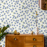 Light Blue floral wallpaper with scattered white and soft blue flowers on a light background in a cozy bedroom setting