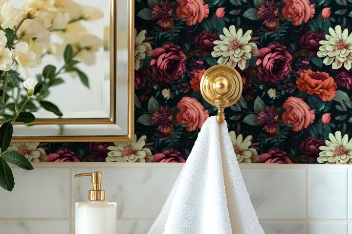 Moody floral wallpaper with ivory and coral blooms on dark teal wall paired with gold accents in bathroom