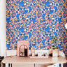 Colorful floral wallpaper with cobalt blue and blush peach flowers in a playful teen bedroom with pink decor and modern styling.
