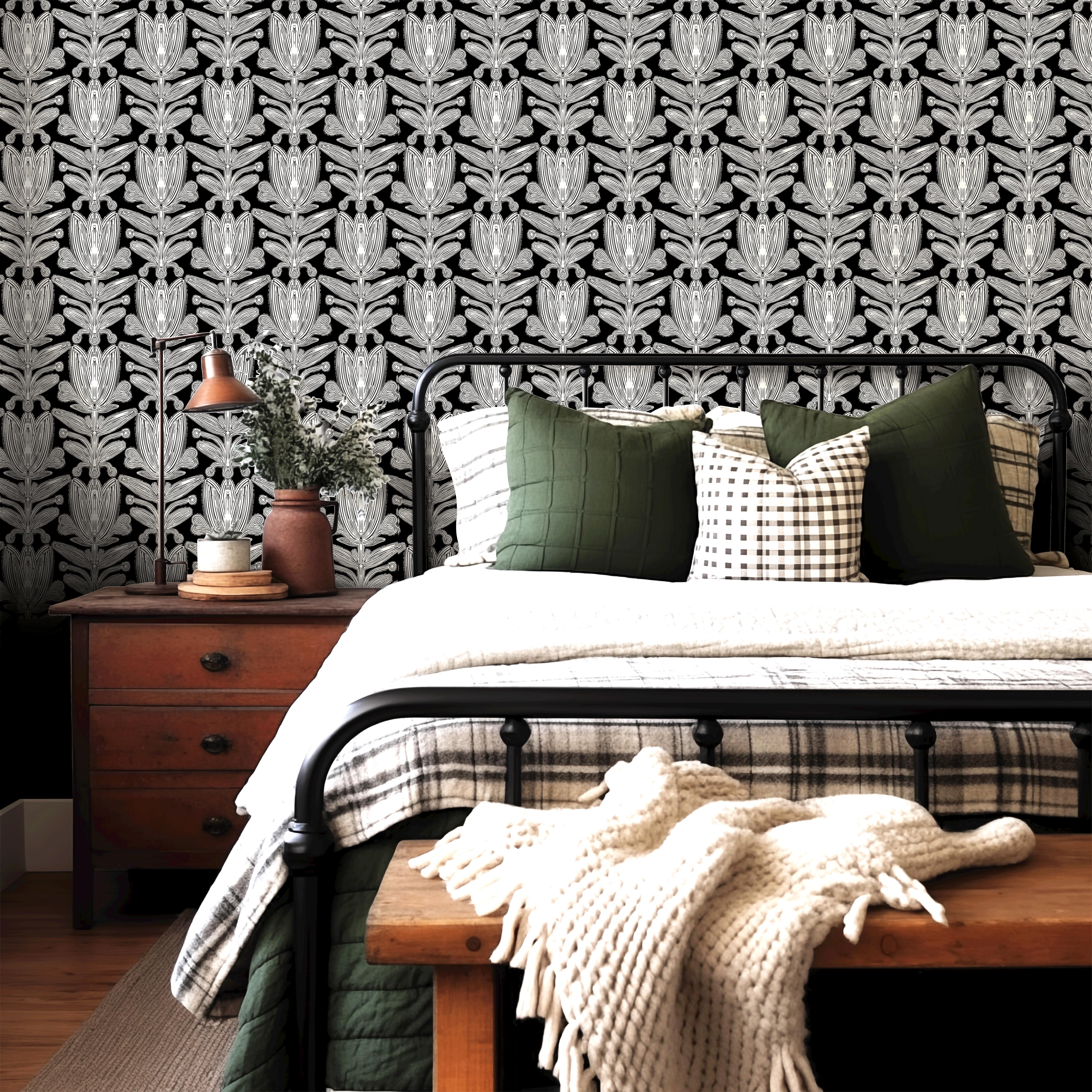  black floral wallpaper behind metal bed with green pillows wood nightstand and plaid bedding